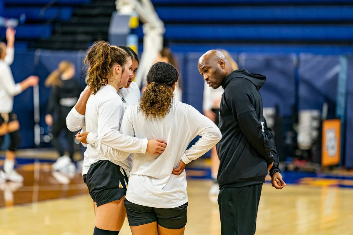 A coach talking with players during practice on a basketball court