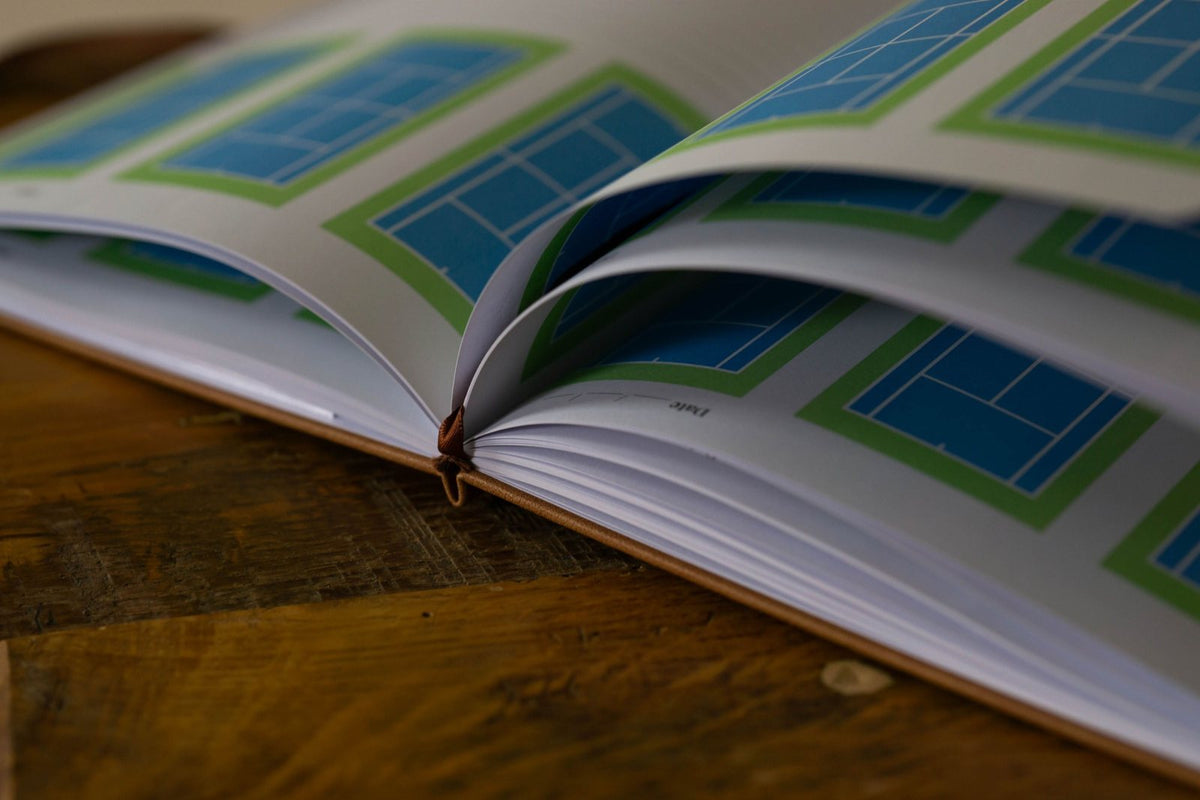 The Tennis Edition journal open showing tennis court diagrams